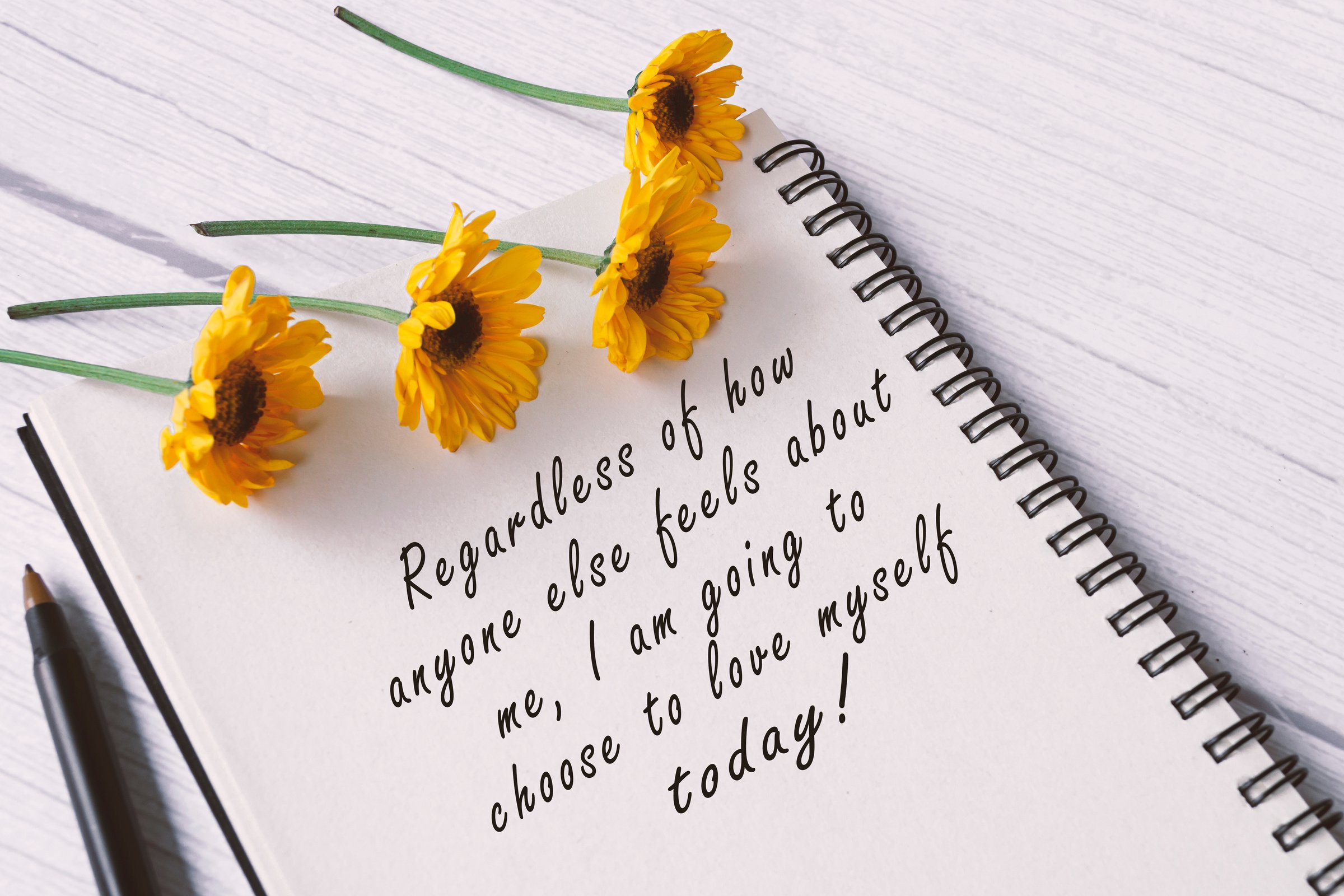 Motivational quote on note book with sunflowers on wooden de