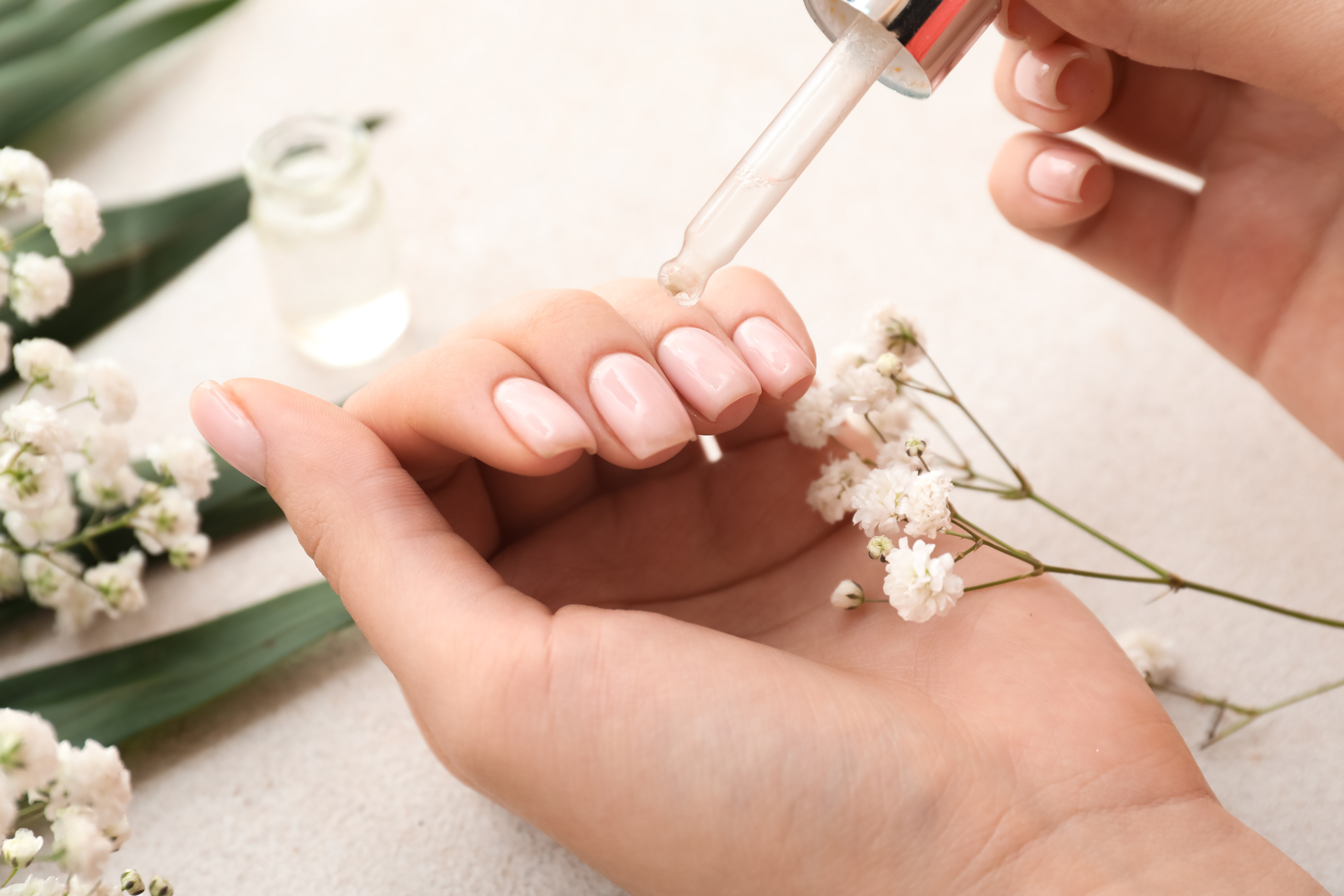 Woman Applying Healthy Cuticle Oil on Light Background, Closeup