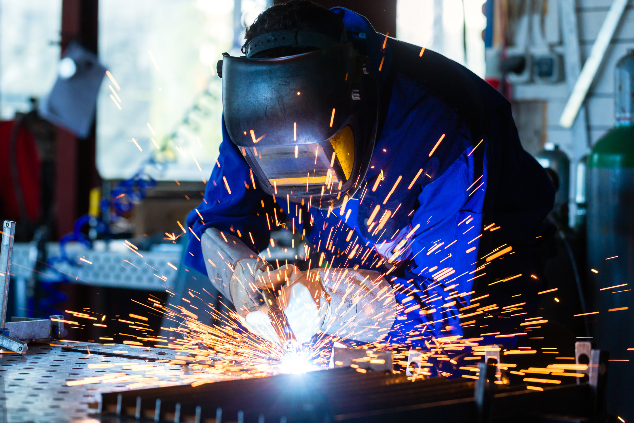 Welder Welding Metal in Workshop with Sparks