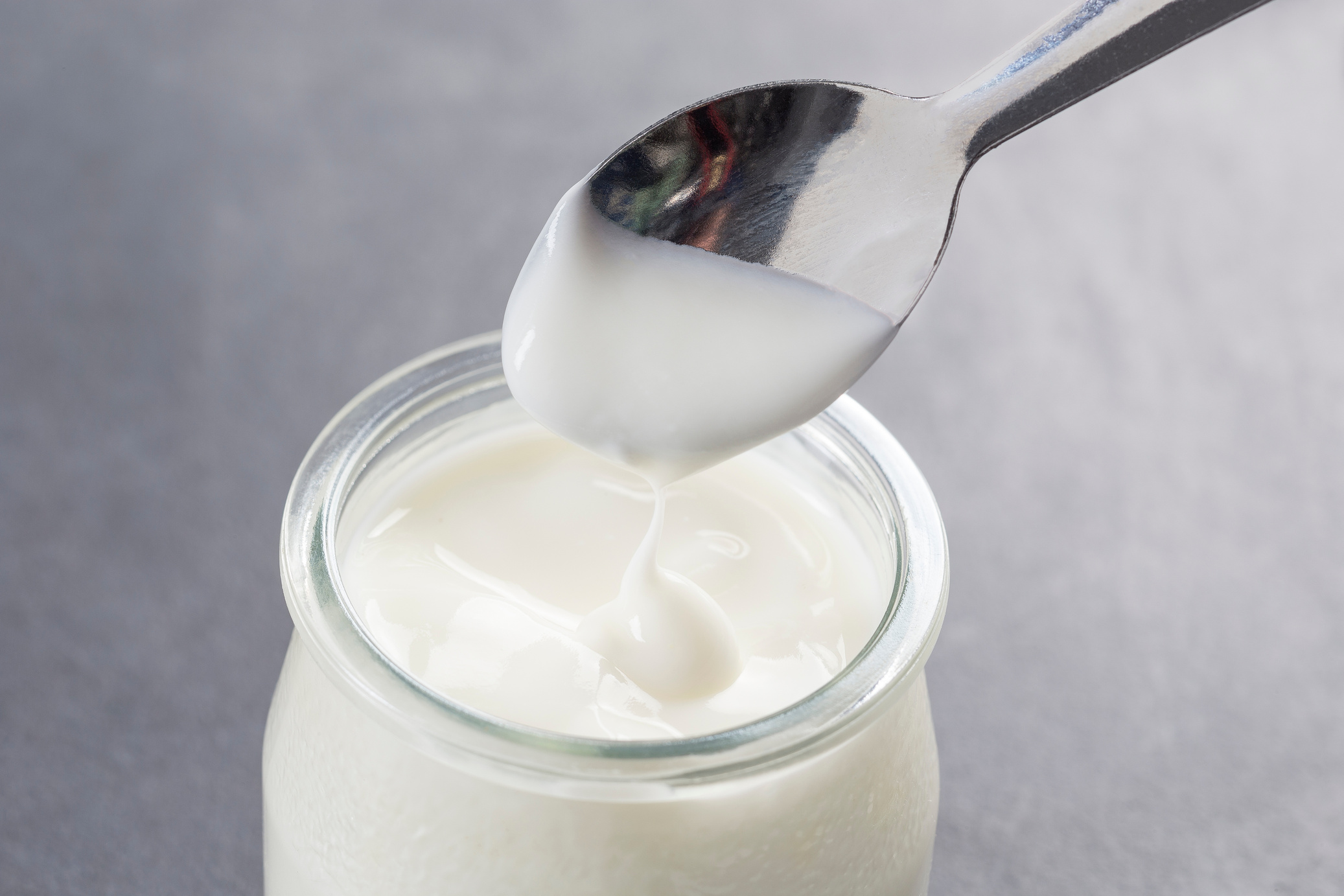 yogurt with spoon isolated on grey background